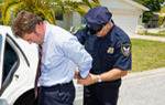 stock photo : Businessman being handcuffed and placed under arrest in front of his home.